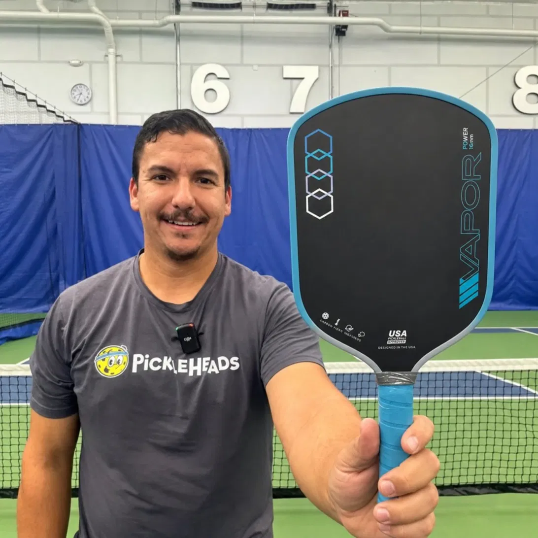 Indoor pickleball player holding paddle toward the camera